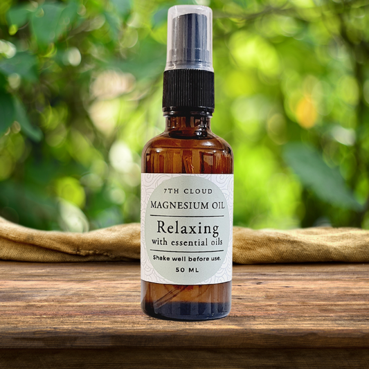 A 50ml amber glass bottle of magnesium oil relaxing spray with essential oils, labeled '7th Cloud Magnesium Oil Relaxing' and placed on a wooden surface in a natural outdoor setting.