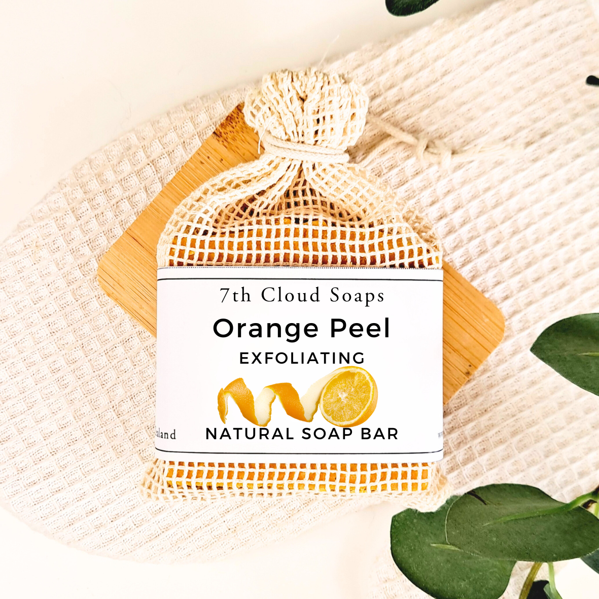 Orange Peel Exfoliating Natural Soap Bar from 7th Cloud Soaps on a textured surface with leaves.
