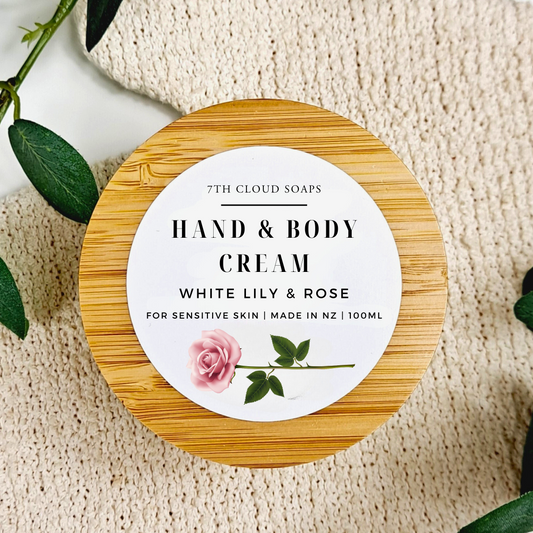 Hand and body cream container with a wooden lid on a textured surface with green leaves.