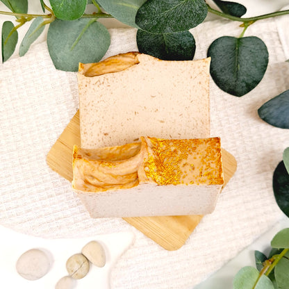 Two soap bars on a wooden stand with green leaves in the background