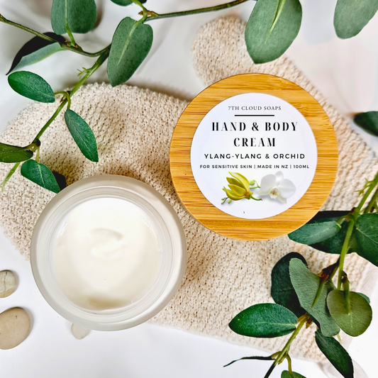 A glass jar with a bamboo lid labeled 'HAND & BODY CREAM YLANG-YLANG & ORCHID' is displayed next to the open jar 