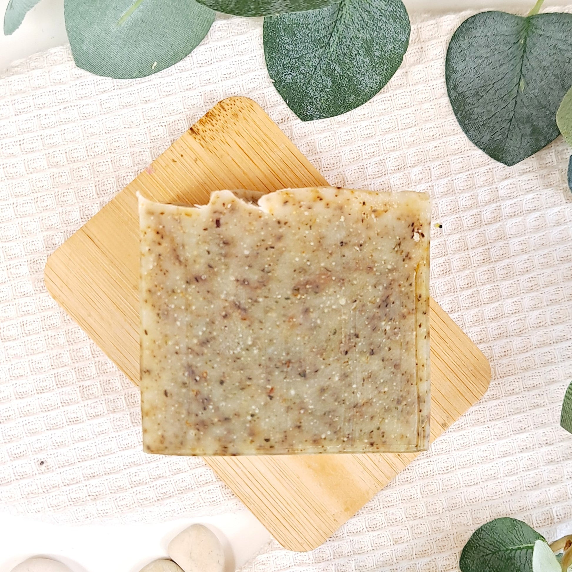 Bar of soap on a wooden board with eucalyptus leaves in the background