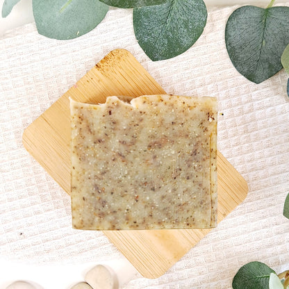Bar of soap on a wooden board with eucalyptus leaves in the background