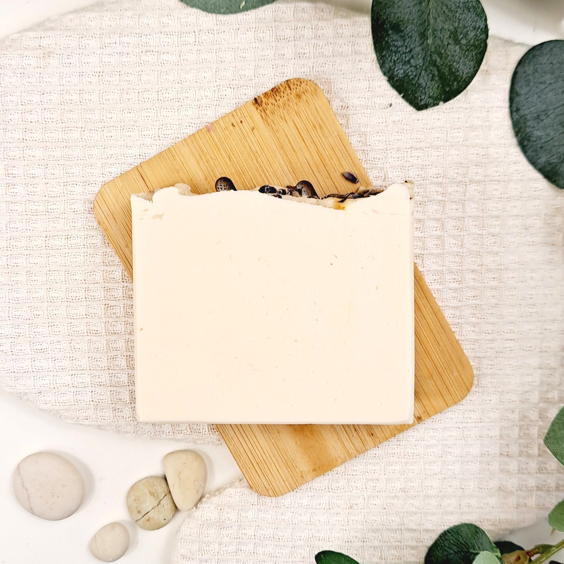 Bar of soap on a wooden board with natural elements on a light background